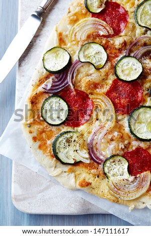 Pizza with salami, zucchini and onion on marble background