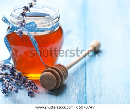 Lavender honey and honey dipper on wooden background