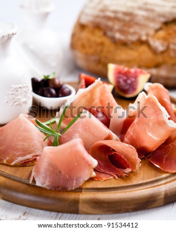 Dry cured ham with olives and fig on chopping board