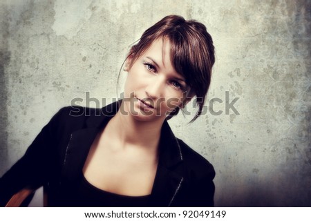 Portrait of brunette woman sitting on a chair against grunge background (textured image)