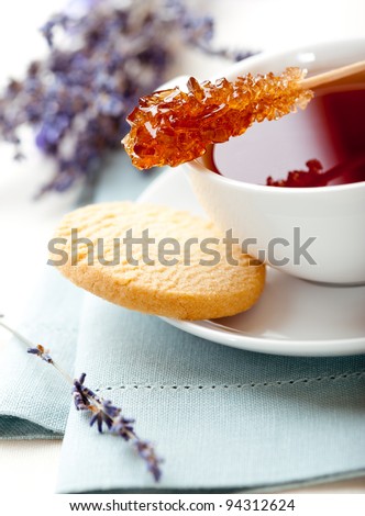 Cup of tea with sugar stick and butter biscuit
