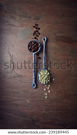 Dark roasted coffee beans and green coffee beans on iron spoons