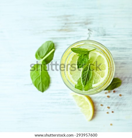 Glass of homemade lemonade with mint and lemon wedges