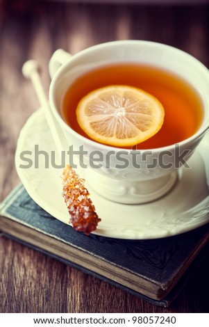Cup of Tea with Lemon and Sugar Stick on a Old Book