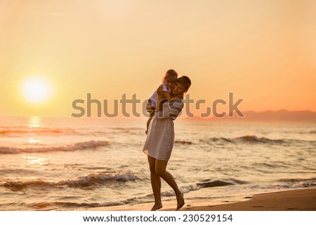 Happy mother holding her daughter on the beach at sunset, summer time. Italy, Forte dei Marmi