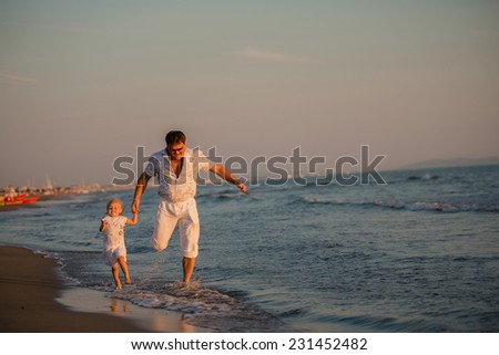 Happy father running with his daughter by the seaside at sunset, summer time. Fatherhood concepts, Italy, Forte dei Marmi