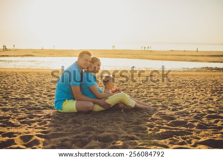 family sitting on the beach at sunrise