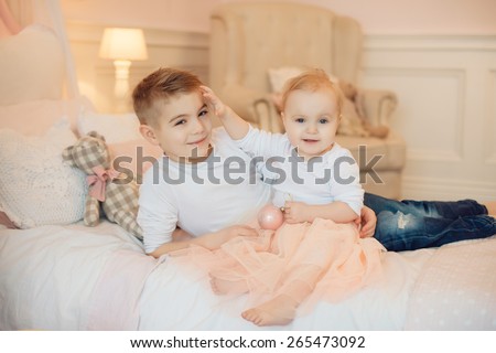brother and sister playing sitting on a bed, cuddling