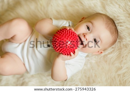 newborn baby boy playing with a red ball