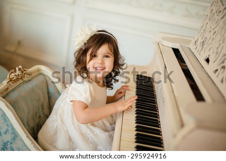 beautiful little girl playing piano in light room