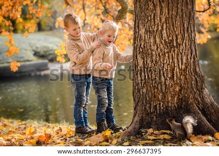 Happy kids feeds a little squirrel in autumn park