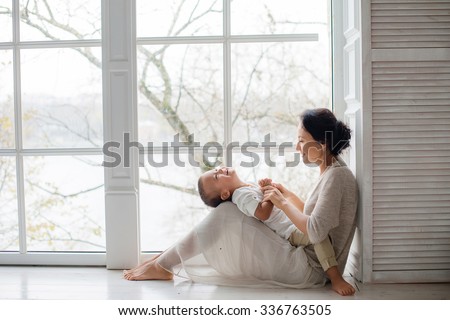 Mother with baby sitting at the window and play