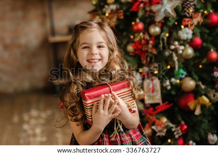 Happy little smiling girl with christmas gift box.