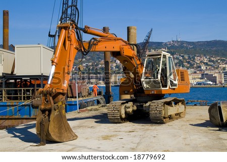 An excavator working in a industrial harbor with sea background