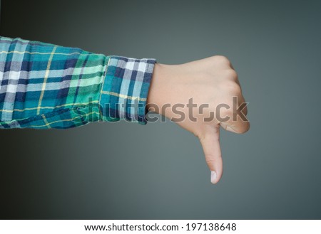 Thumbs down hand, green plaid shirt sleeve, dark green background.