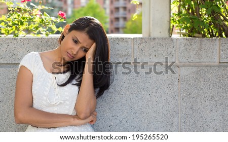 Closeup portrait, dull upset sad young woman in white dress sitting on bench, really depressed, down about something, isolated gray background. Negative emotion facial expression feeling body language