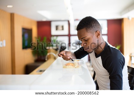 Closeup portrait young handsome man eating noodles, sitting at white table, isolated luxurious, urban indoor background