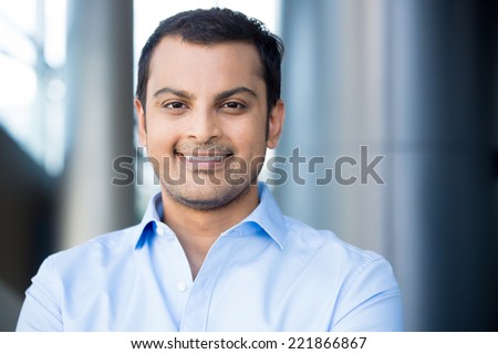 Closeup headshot portrait, happy handsome business man, smiling, in blue shirt,confident and friendly on isolated office interior background. Corporate success