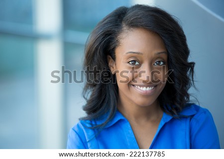 Closeup portrait, young professional, beautiful confident woman in blue shirt, friendly personality, smiling isolated indoors office background. Positive human emotions