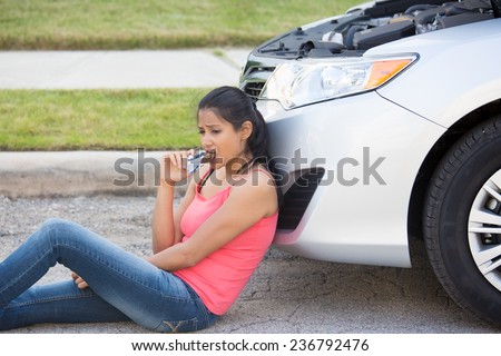 Closeup portrait, hungry young woman in pink tanktop, sitting on road, frustrated by car problems.  Eating energy chocolate bar while waiting for help, isolated road and grass background.