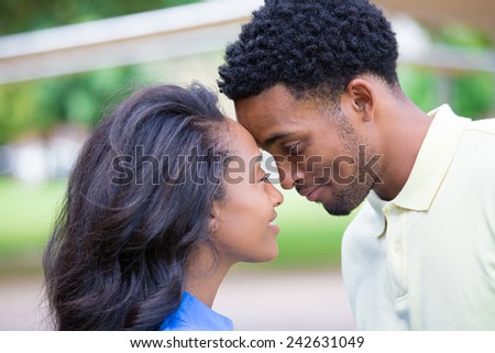 Closeup portrait of a young couple, guy in yellow shirt looking into woman\'s eyes with blue shirt, head to head, happy moments, positive human emotions, isolated outside outdoors background