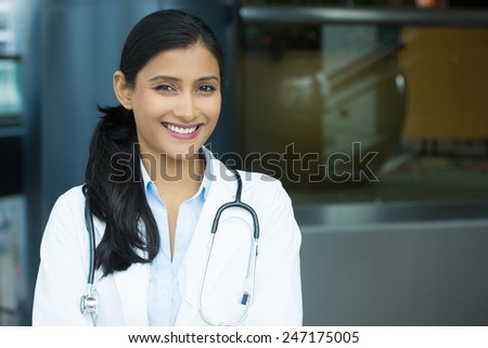Closeup portrait of friendly, smiling confident female doctor, healthcare professional with labcoat and stethoscope, isolated indoors clinic hospital background