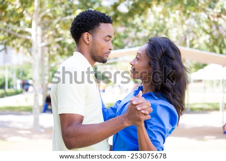 Closeup portrait of a young couple, guy holding woman in arms, looking at each other, dance pose, love and romance concept, positive human emotions on isolated outdoors outside park background.