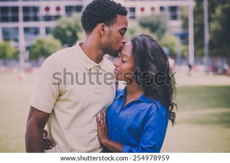 Closeup portrait of a young couple, guy holding woman and kissing face, happy moments, positive human emotions on isolated outdoors outside park background. Retro faded vintage look