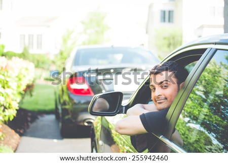 Closeup portrait, young handsome man in his new black car, relaxing, resting face on arms, isolated on outdoors background with vehicle. Retro faded vintage look