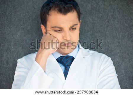 Closeup portrait, young depressed man healthcare practitioner holding face in despair, isolated gray background