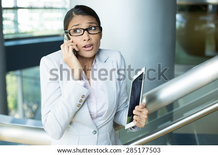 Closeup portrait of pretty busy woman in gray suit and pink shirt holding phone and tablet, sorry and apologizing for her mistakes, caught red-handed, isolated indoors office background