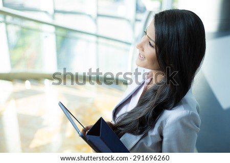 Closeup side view portrait, woman in gray business suit holding handheld tablet and wondering, isolated indoors office background