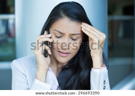Closeup portrait, sad, depressed, unhappy worried young woman talking on phone,  isolated indoors office background. Negative human emotions, facial expressions, feelings, reaction. Bad news.