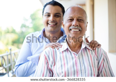 Closeup portrait, family, young man in blue shirt holding older man in striped shirt from behind, happy isolated on outdoors outside balcony background