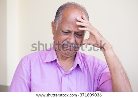 Closeup portrait, morose elderly pensioner, downcast gloomy, resting hand on head, isolated indoors home background