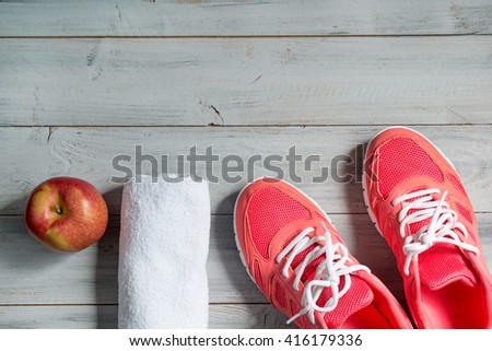 Fitness concept, pink sneakers, red apple and white towel on wooden background, top view