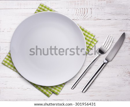 Empty plate, knife, fork and towel over wooden table background. View from top with copy space.
