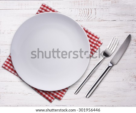 Empty plate, knife, fork and towel over wooden table background. View from top with copy space.
