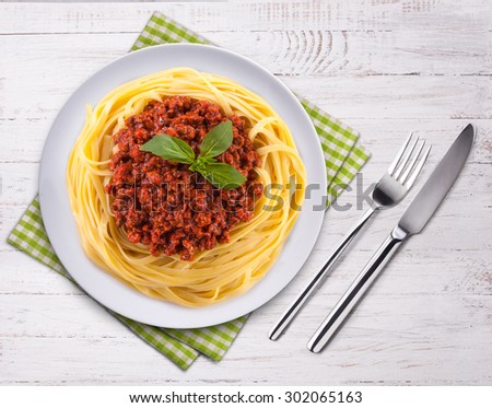 Spaghetti bolognese on the wooden table. Top view. Fork, knife and towel.