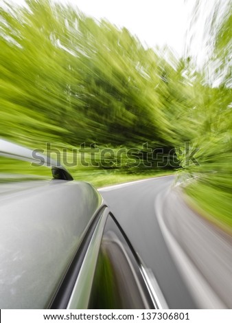 Roof rack view of a caravan car driving fast on a winding road in the woods