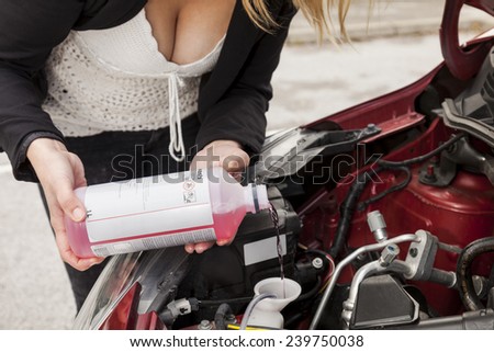 Beautiful woman refiling windscreen washer fluid in the car engine