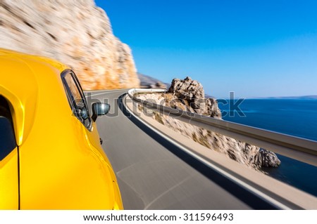 Sports car driving fast on a winding road by the sea