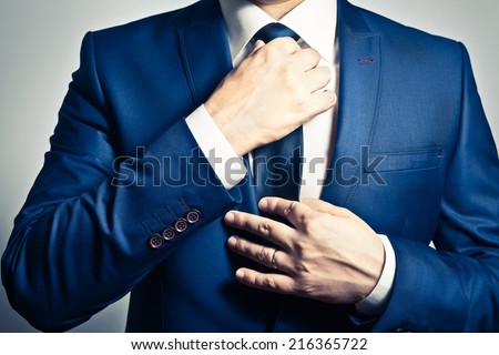 Businessman in blue suit tying the necktie