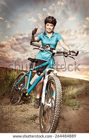 Happy young woman in  sportswear on the racing bike showing thumb up and smiling. Sport concept.