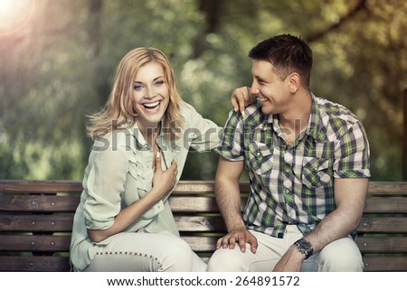 Relationship concept. Young cheerful couple sitting in the park talking and  laughing.