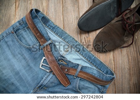 Jeans with a leather belt and leather shoes on a wooden floor.