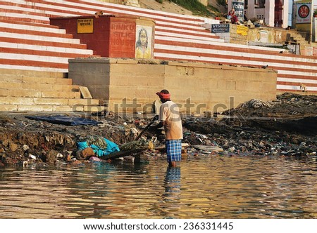 VARANASI,INDIA - OCTOBER 23: Unidentified man washes his clothes in the river Ganga on October 23, 2014 in the holy city of Varanasi, India.