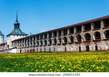 wall of Kirillo-Belozersky Monastery with the tower and field with dandelion