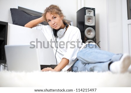 Beautiful woman with headphones and laptop sitting on the floor