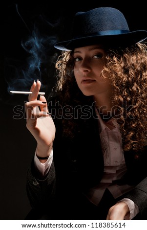 Beautiful woman standing and smoking on the black background